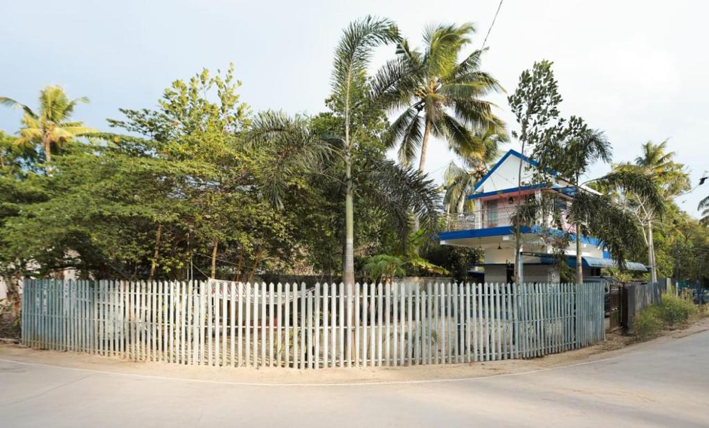 a white fence with a blue house behind it at Penuel marari homesty in Mararikulam