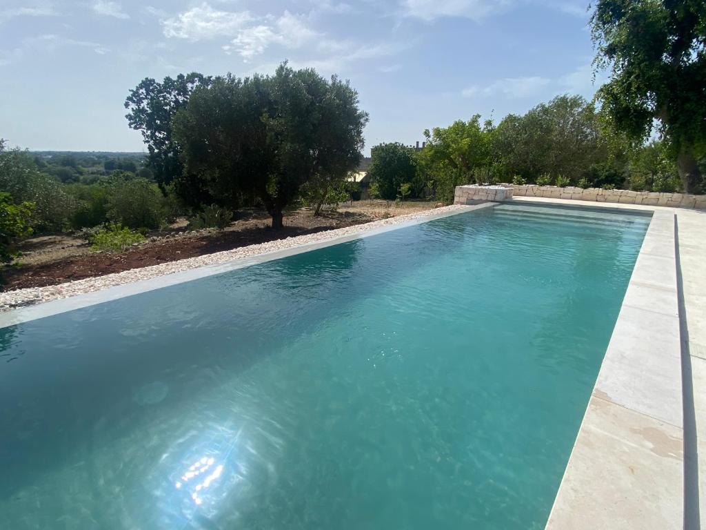 une grande piscine avec de l'eau bleue dans l'établissement Trullo Pugliarmonia, à Fasano