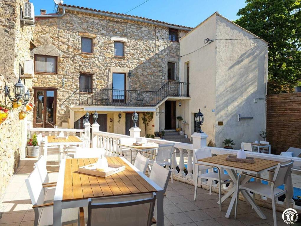 a patio with tables and chairs and a building at La maison millesime in La Caunette