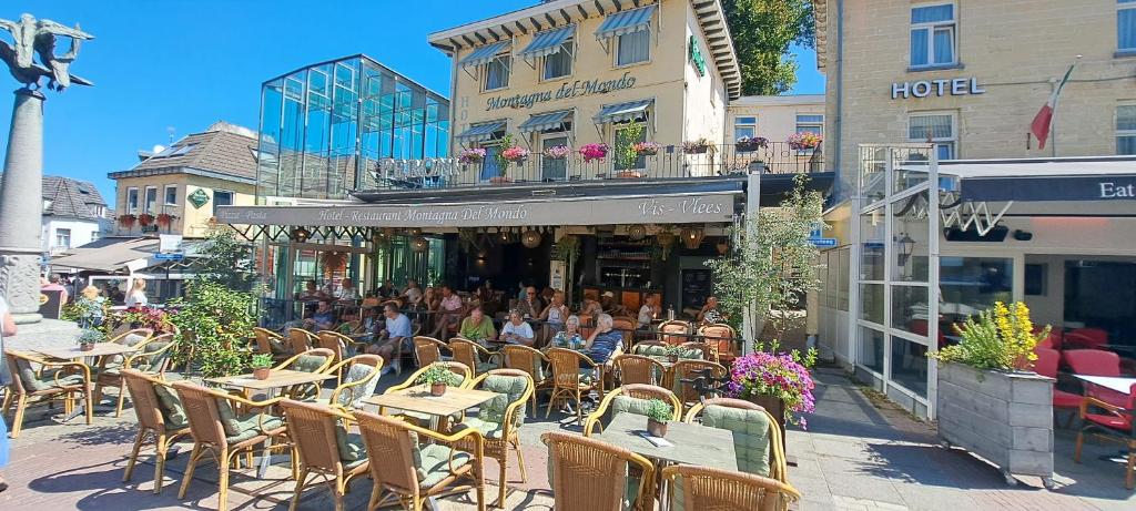 a group of people sitting at tables outside a restaurant at Hotel Montagna Delmondo in Valkenburg