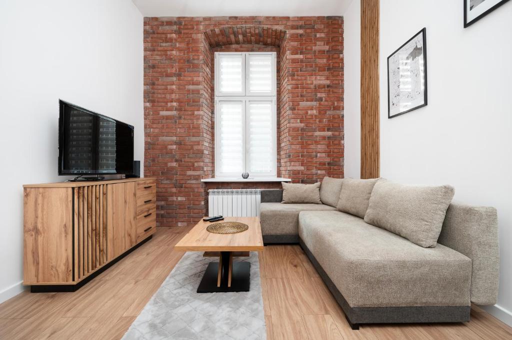 Una sala de estar con un sofá y un televisor. en Piotrkowska Luxury Studio with Mezzanine by BookingHost, en Łódź