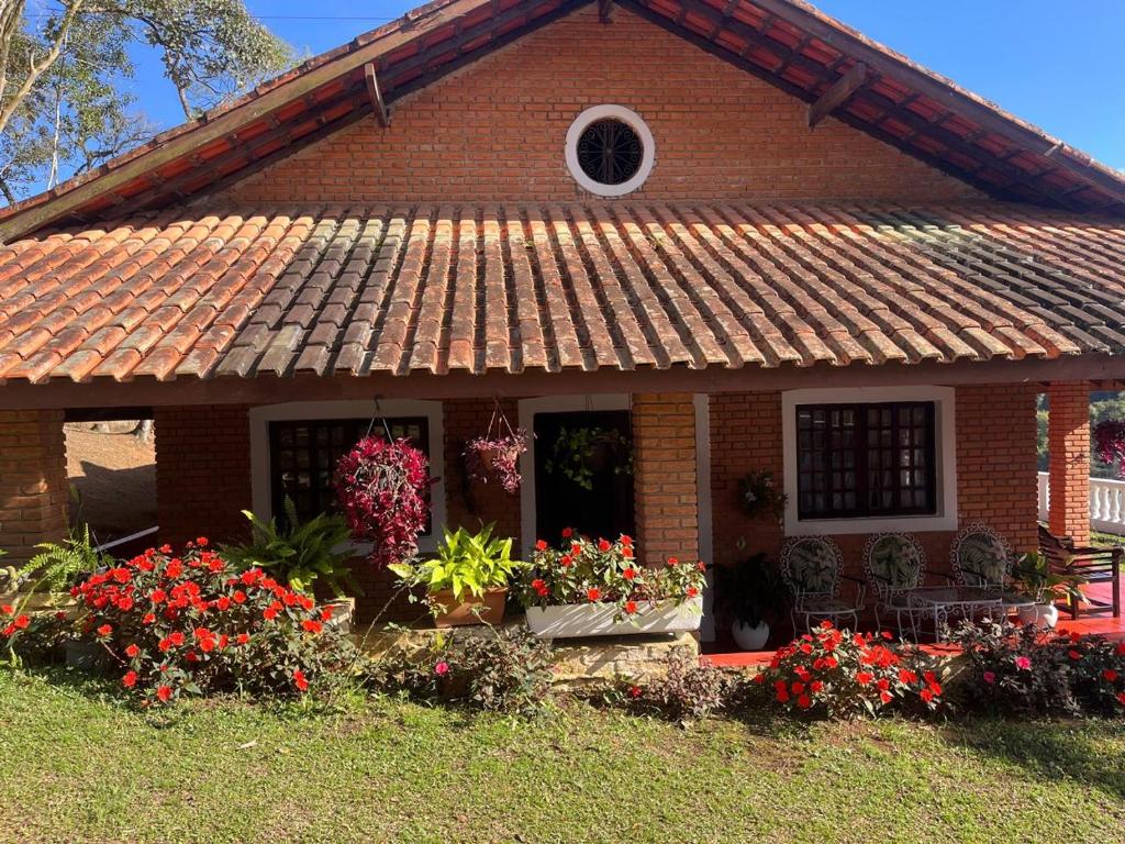 une maison en briques avec des fleurs devant elle dans l'établissement Chácara Vovô João, à São Paulo