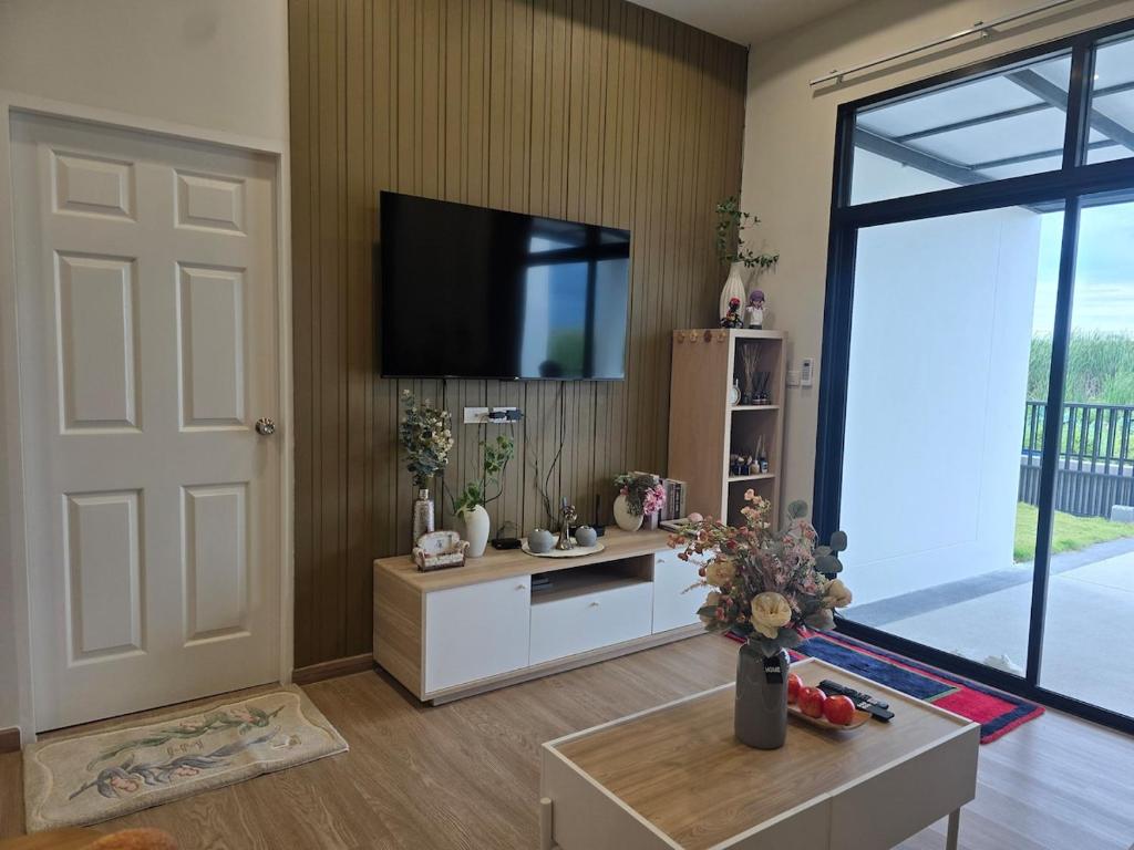 a living room with a television on a wall at Klong Loung House Airport transportation service in Pathum Thani