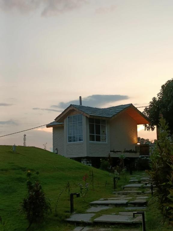a house sitting on top of a grassy hill at whispering roots resort in Jim Corbett