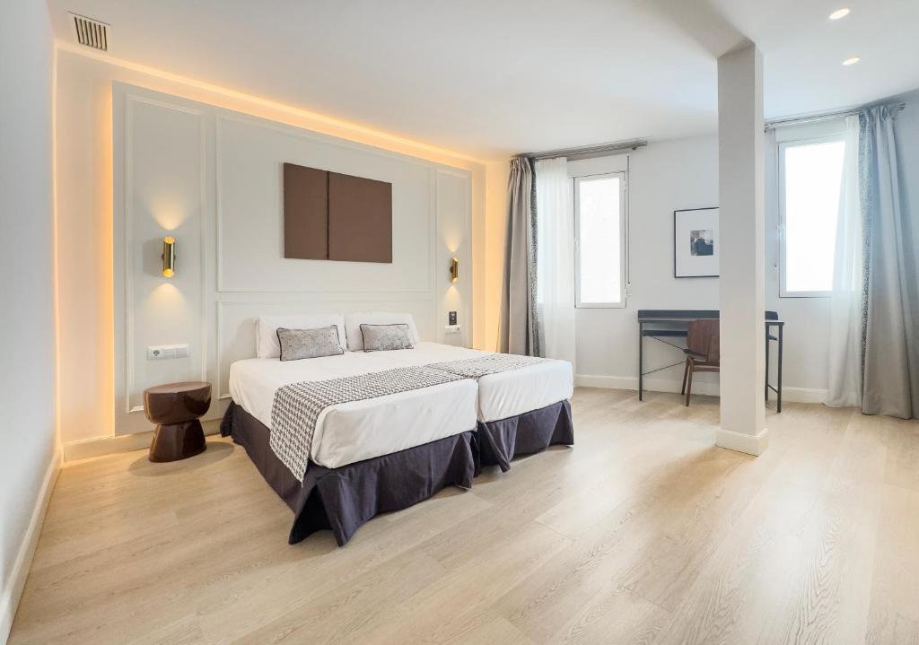 a bedroom with a bed and a table and windows at Ópera Stays by Charming in Madrid