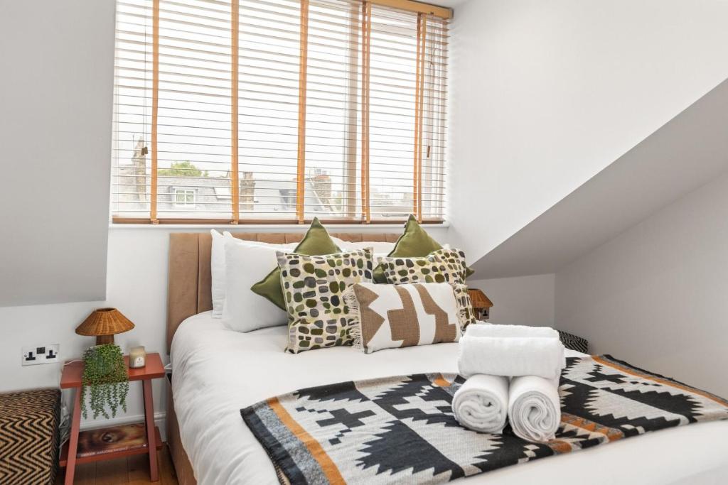 Un dormitorio con una cama con almohadas y una ventana. en Sunny TopFloor 1BR , Balcony Views Sleeps 3, en Londres