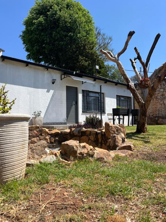 ein weißes Haus mit einem Baum und einigen Felsen in der Unterkunft Cozy Cottage on 5th Avenue in Johannesburg