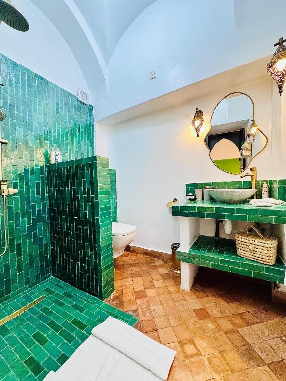 une salle de bain avec une douche carrelée verte et un lavabo dans l'établissement Riad Dar Beldia and Spa, à Marrakech