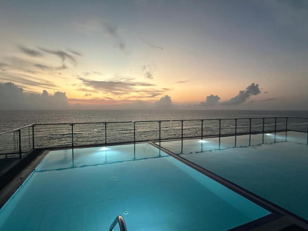 a swimming pool with the ocean in the background at The Bay in Dehiwala