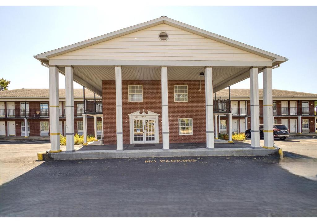 a red brick building with a large pavilion in a parking lot at Capital O First Heritage Inn Rantoul IL I 57 in Rantoul
