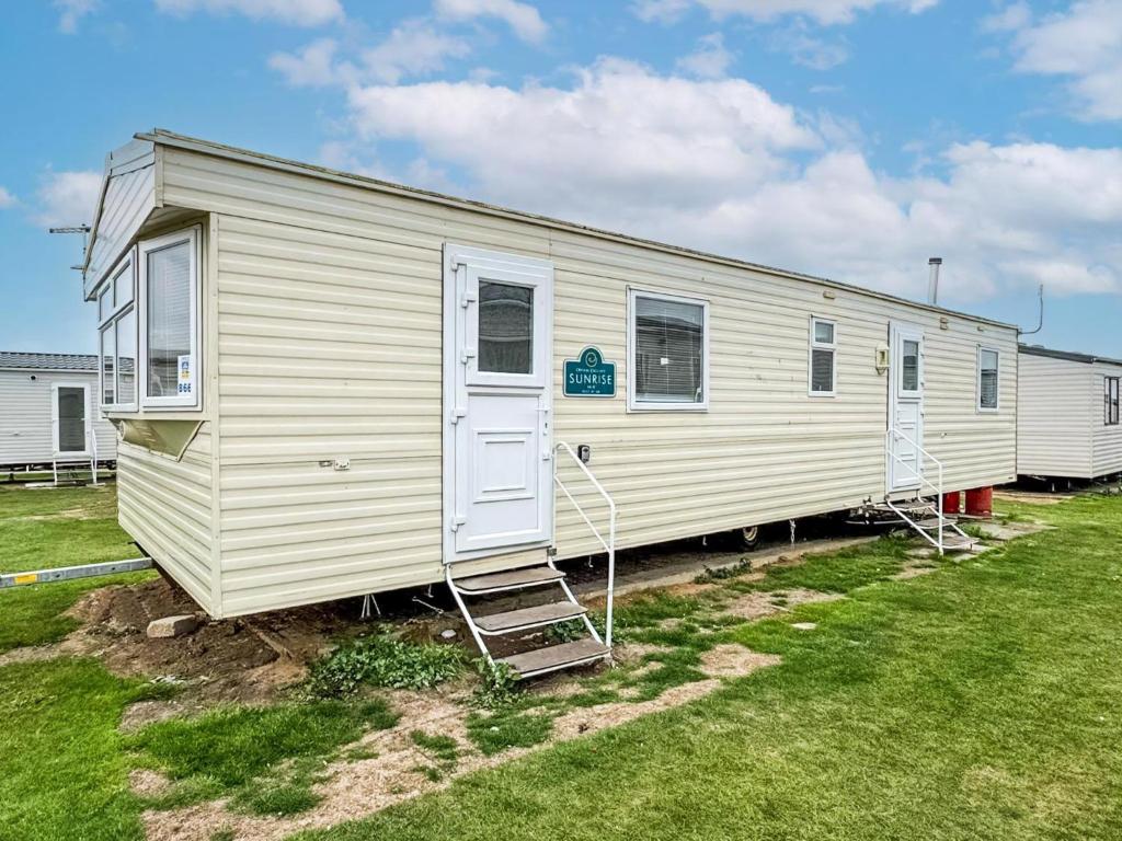 a white mobile home with a ladder in a yard at Lovely 8 Berth Caravan At Harts Holiday Park In Kent Ref 74066B in Sheerness