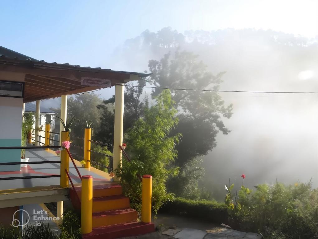 a misty view of a house with stairs and trees at The Himalayan Heaven Homestay, Binsar in Binsar