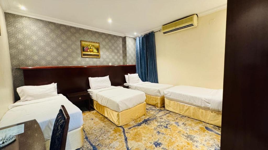 a hotel room with three beds and a window at الوافدين in Jarwal