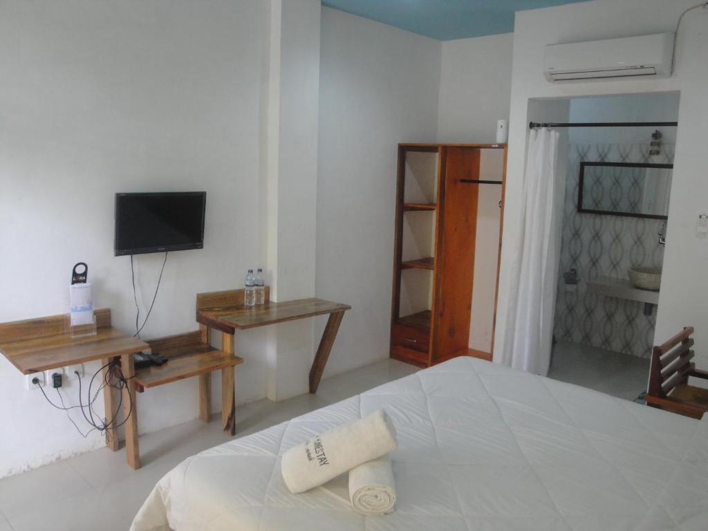 a white bedroom with a bed and a television at Lara Homestay in Kuta Lombok