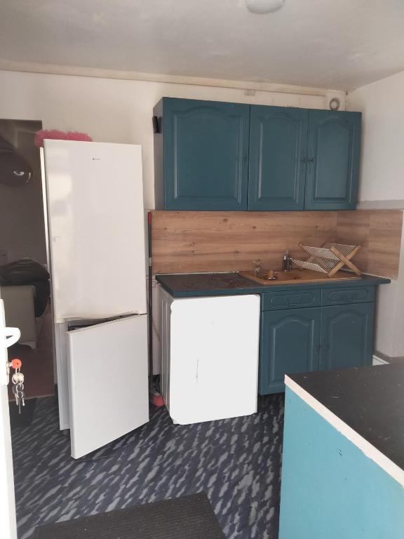 a kitchen with blue cabinets and a white refrigerator at Appartement Cosy à Nemours Hameau Chaintreauville in Saint-Pierre-lès-Nemours