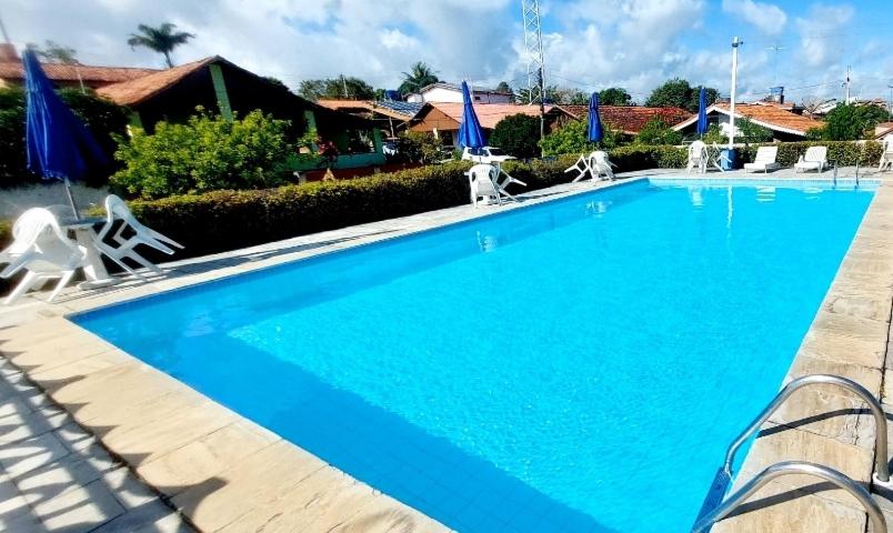 a large blue swimming pool with white chairs around it at Cond CHACARA BAVIERA in Gravatá
