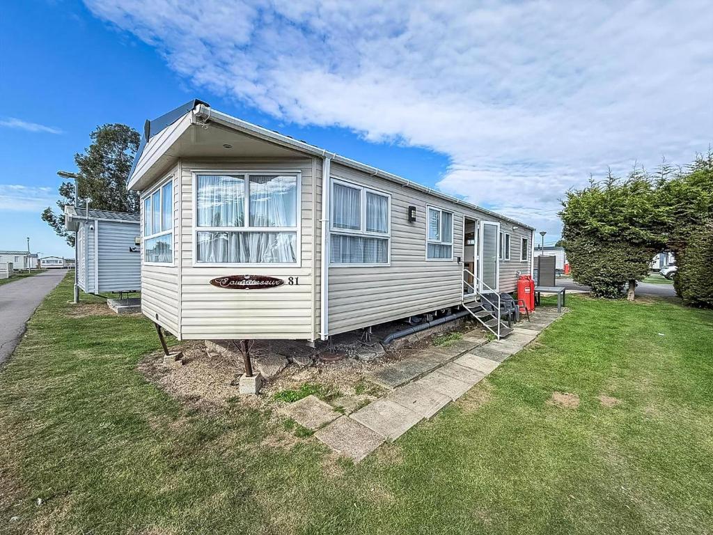 a white tiny house sitting on top of a yard at Superb Caravan At Steeple Bay Holiday Park In Essex, Sleeps 6 Ref 36081D in Southminster