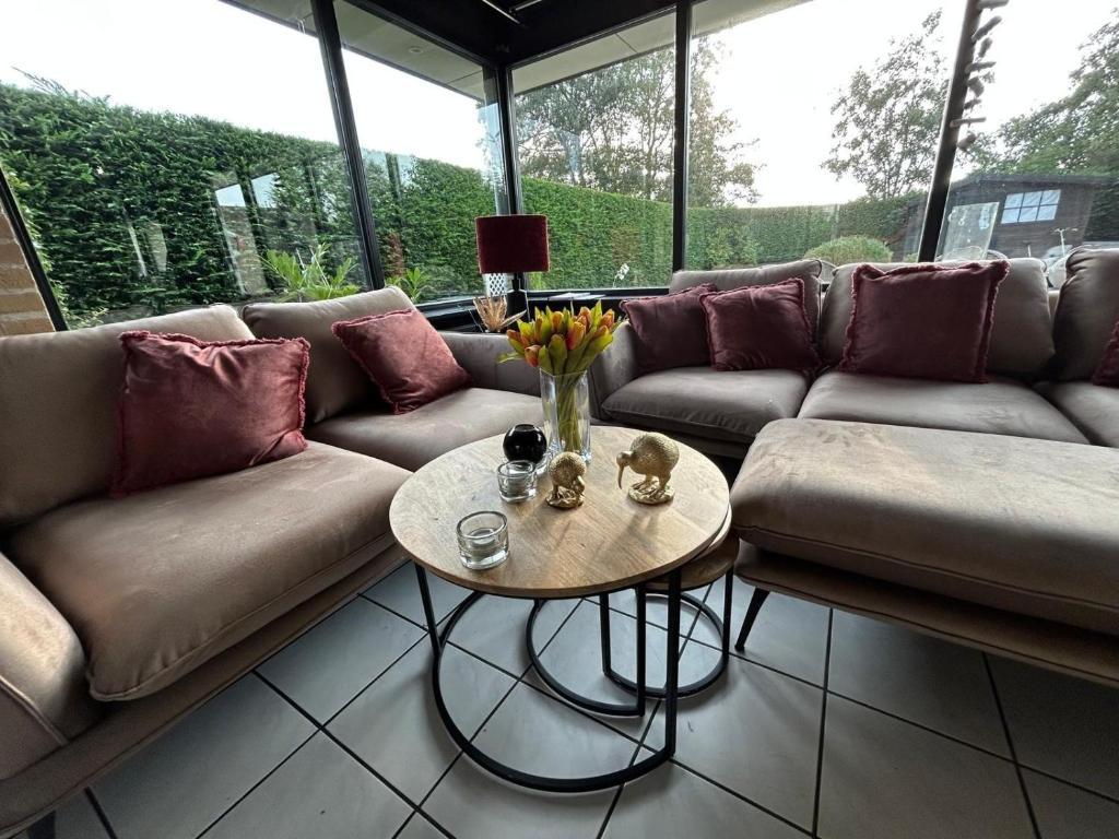 a living room with a couch and a table at Moderner gepflegter, ruhiger Bungalow, Strandnah mit großen, uneinsehbaren Garten, Terrassenüberdachung in Sint Maartenszee