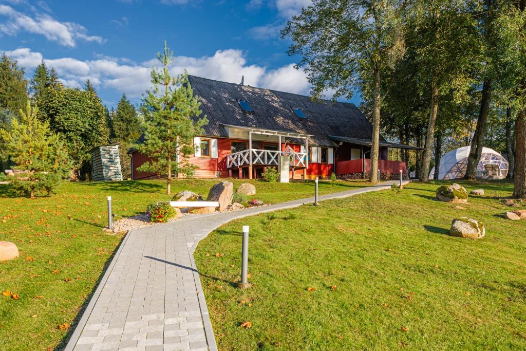 a house with a walkway in front of a yard at Namas su vaizdu į ežerą "Giliaus Nendrė" in Tytuvėnai