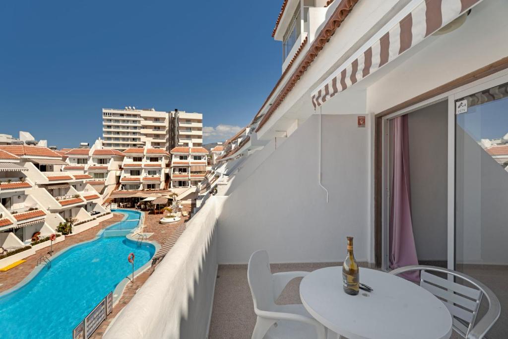 a balcony with a table and chairs and a swimming pool at Las Floritas in Playa de las Americas