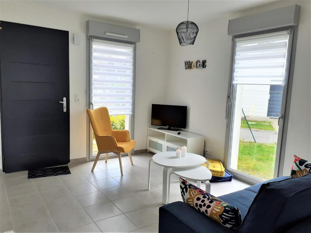 ein Wohnzimmer mit einer Couch, einem Tisch und einem Fernseher in der Unterkunft Maison familiale, proche des plages et des commerces in Piriac-sur-Mer