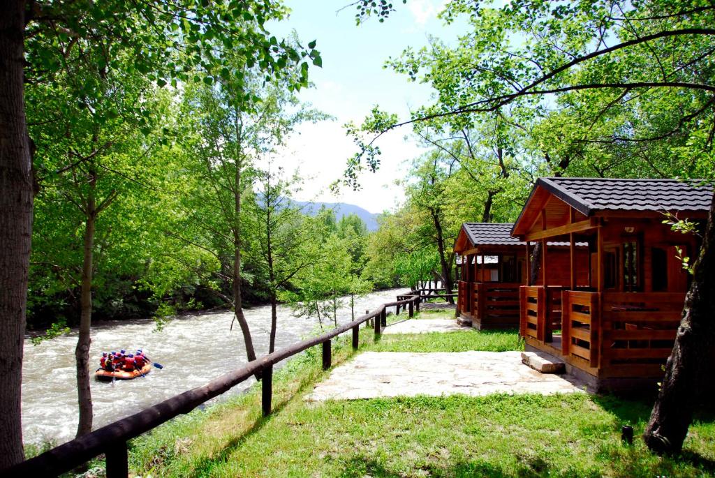 una cabaña junto a un río con gente en una balsa en Camping Noguera Pallaresa, en Sort