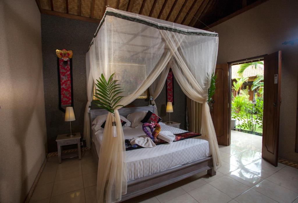 a bedroom with a bed with a canopy at Global Lodge Pemuteran in Pemuteran