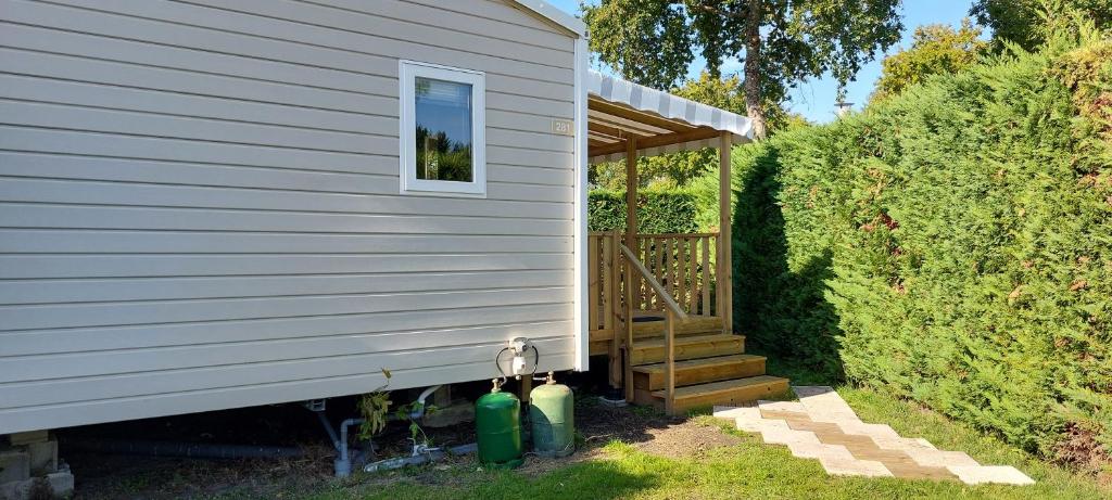 una casa con porche y escaleras junto a un seto en Salsa confort, en Les Mathes