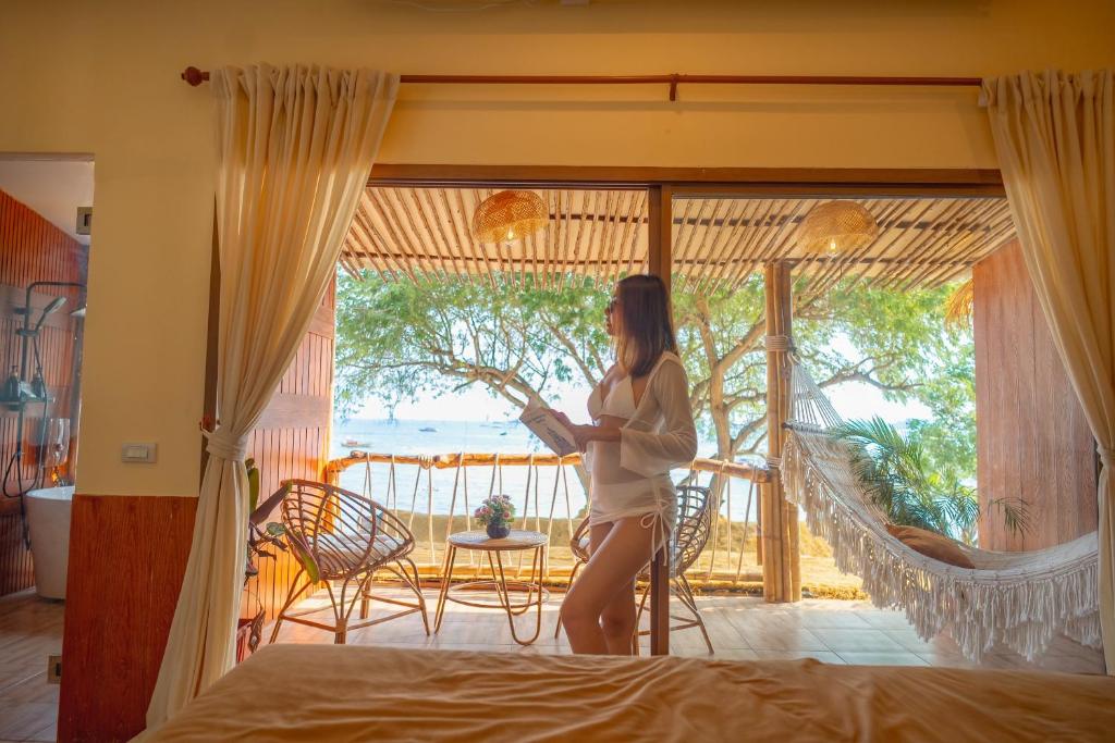 a woman standing in a bedroom with a view of the ocean at Bamboo Seaview Koh Larn Second Floor - 2nd Floor in Ko Sak