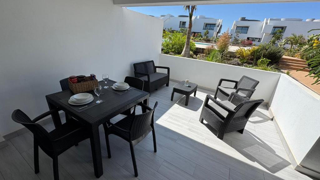 Un patio con una mesa y sillas en un balcón. en Casilla de Costa Luxury home, en La Oliva