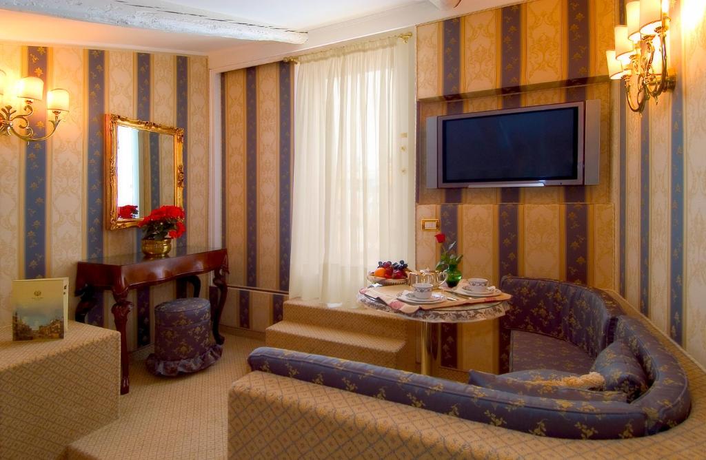 a living room with a couch and a tv on a wall at Hotel Concordia in Venice