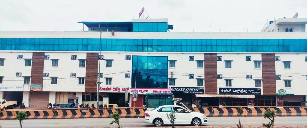 a white car parked in front of a building at Embassy Grand in Jāmb