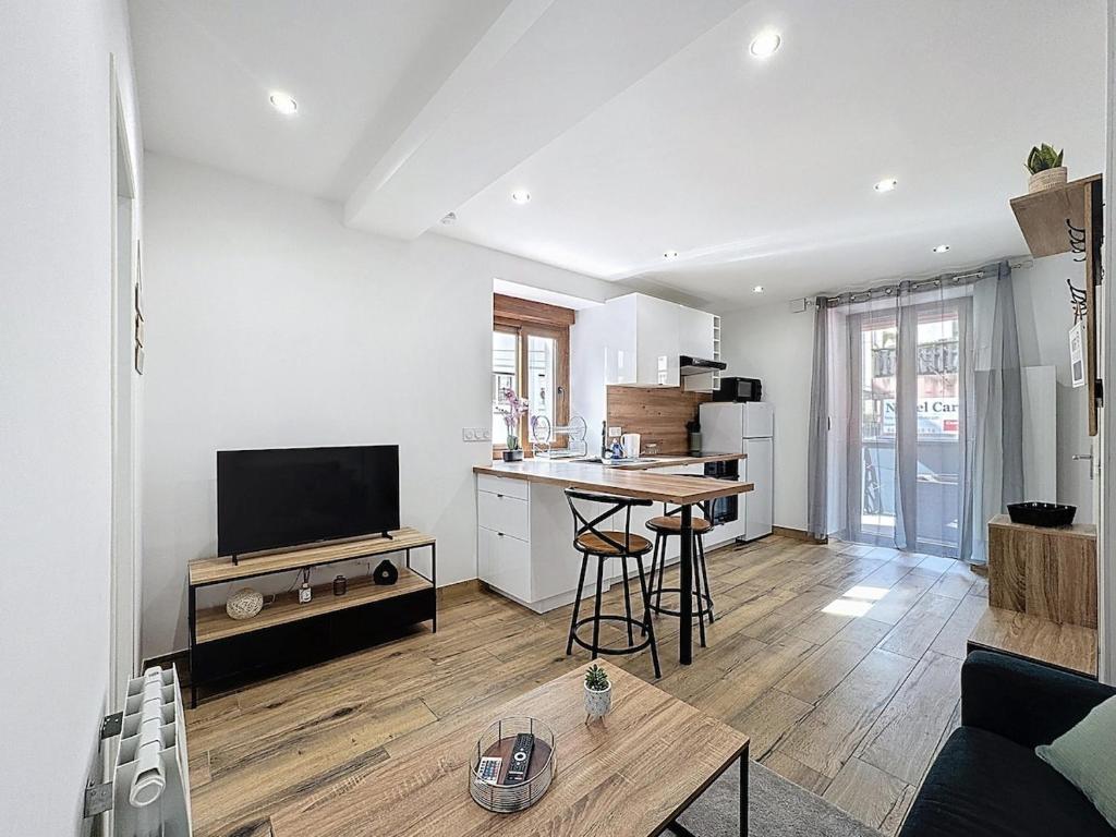 a kitchen and living room with a table and a television at Le Cocon - 5min gare à pied - Balcon - Centre ville in Bellegarde-sur-Valserine