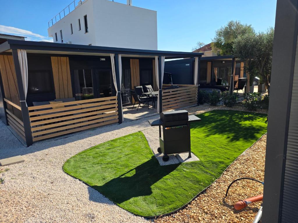 a yard with a house with grass and a grill at Villa 11 Limoni in Sukošan