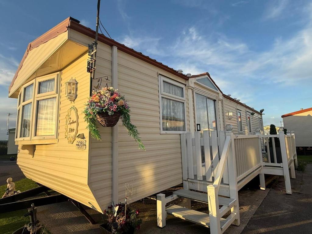 a yellow tiny house with a porch and stairs at 2 Bedroom Caravan - Sleeps 6 - Seaside Parking in Kinmel Bay