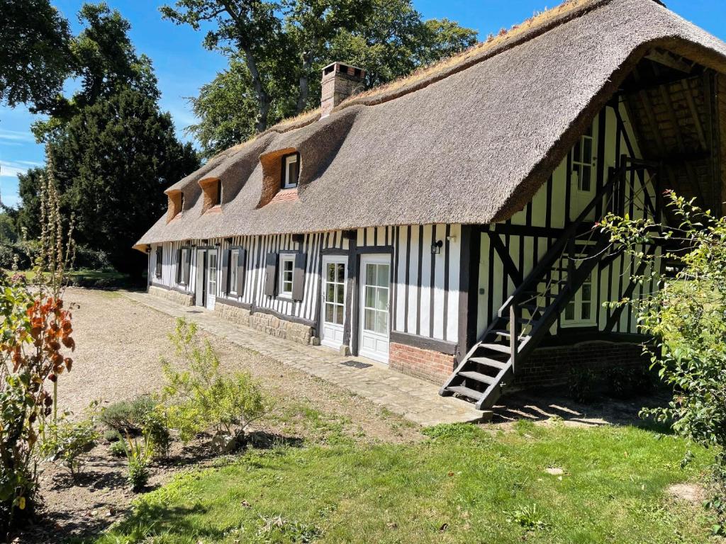 an old house with a thatched roof and a yard at Clos de Leger in Pleine-sève
