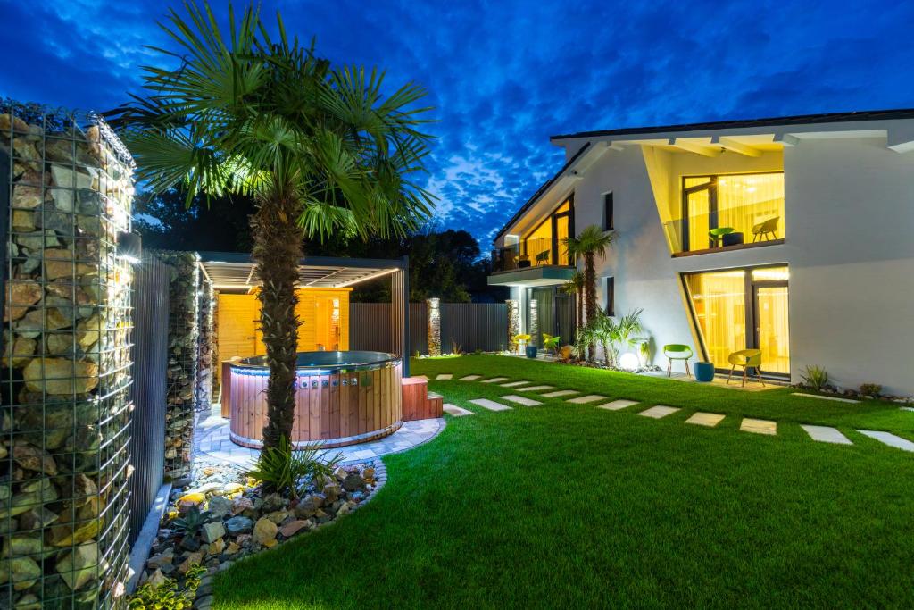 a house with a palm tree in the yard at Mark AquaHouse in Gyula