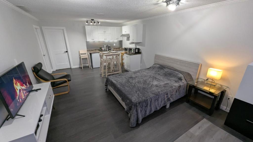 a bedroom with a bed and a kitchen with a table at Modern unit on Burke Mountain - FIFA 2026 in Port Coquitlam