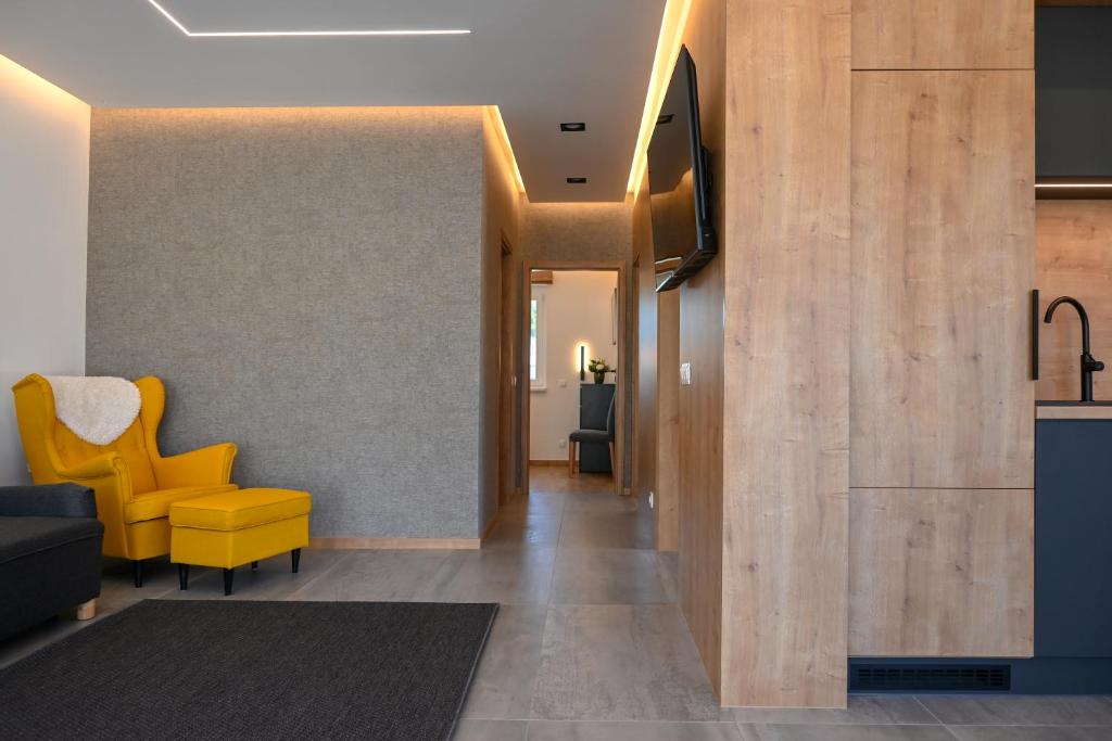 a hallway with a yellow chair and a living room at L'ari-Fáry Home in Sárvár