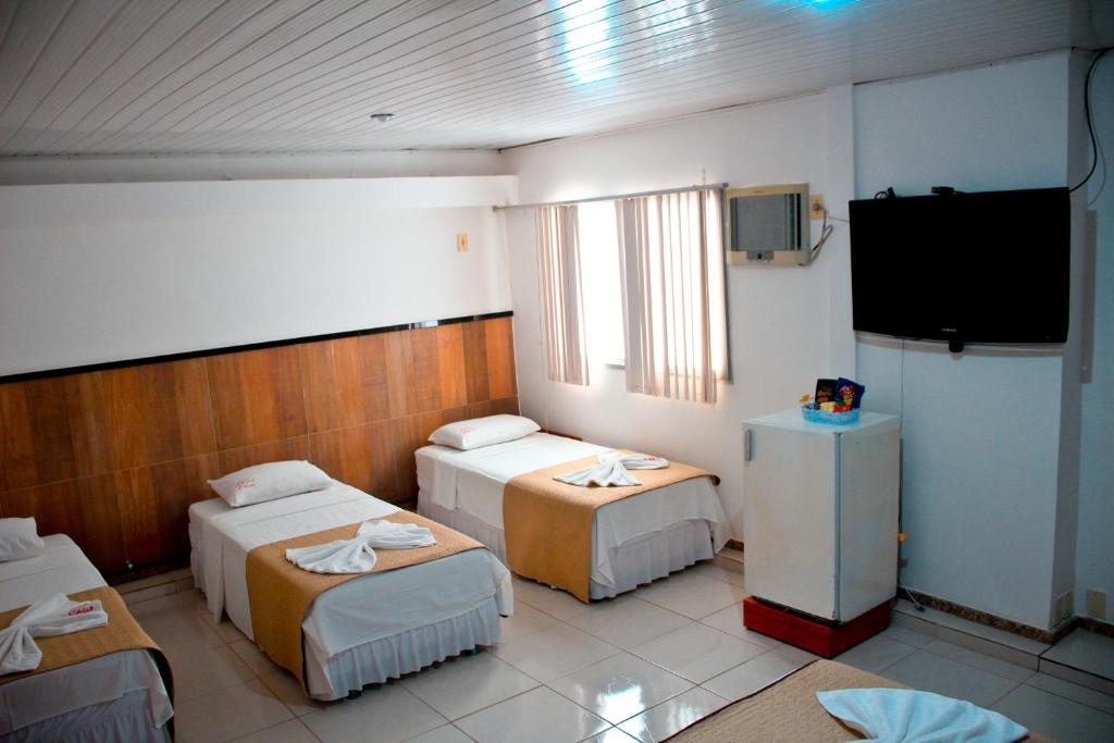 a room with three beds and a flat screen tv at Pousada Solar da Praia in Guarapari