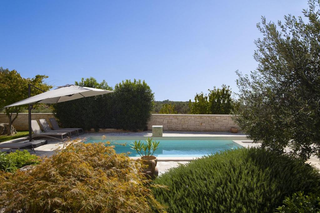a swimming pool with an umbrella and a table and chairs at Villa Mason with Heated Pool and mini Wellness in Rovinjsko Selo