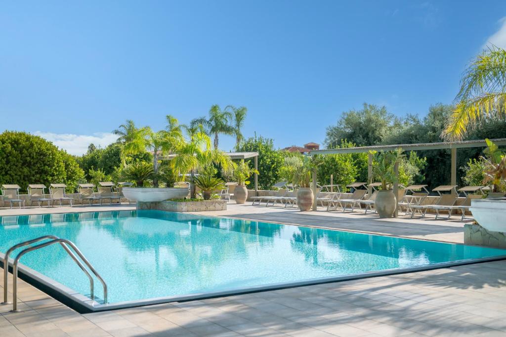 a swimming pool in a resort with tables and chairs at Terra Dei Limoni in Noto Marina