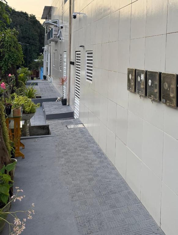 an empty alley with a white wall and some plants at Cantinho Aconchegante - Quarto com Ar-cond 2 in Bayeux