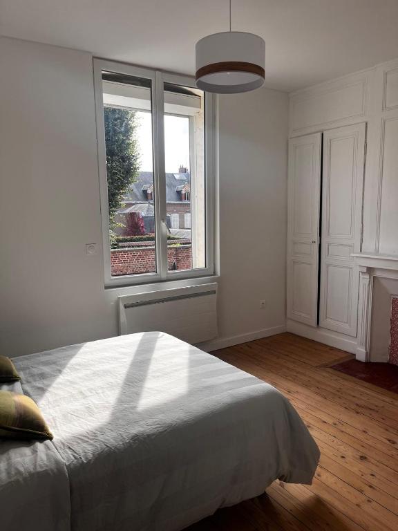 een witte slaapkamer met een bed en een raam bij Maison cosy proche saint-leu et centre-ville in Amiens