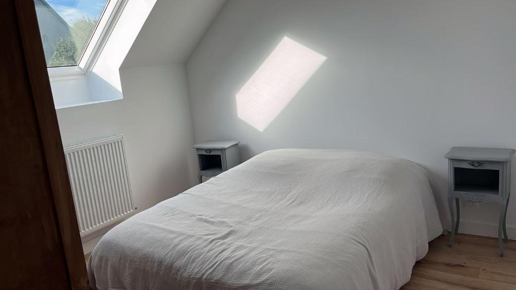 a white bed in a room with a window at Charmant corps de ferme - Proche de la mer in Plougonvelin