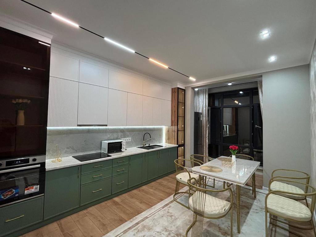a kitchen with green cabinets and a table with chairs at Assu in Taraz