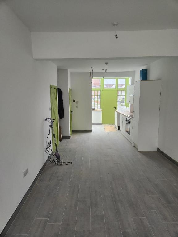 an empty room with white walls and a kitchen with green doors at Main Wasall High Street flat above shop in Walsall