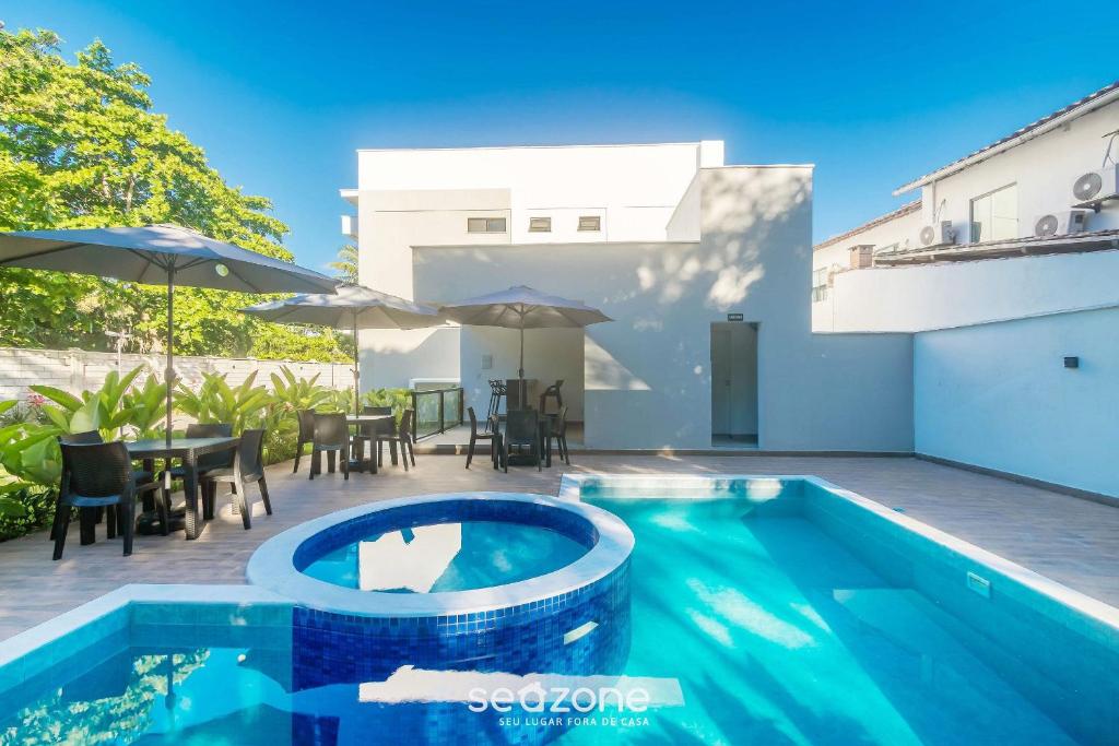 a swimming pool next to a patio with a table and chairs at Estadia completa com piscina e a 350m da Praia PRY in Porto Seguro