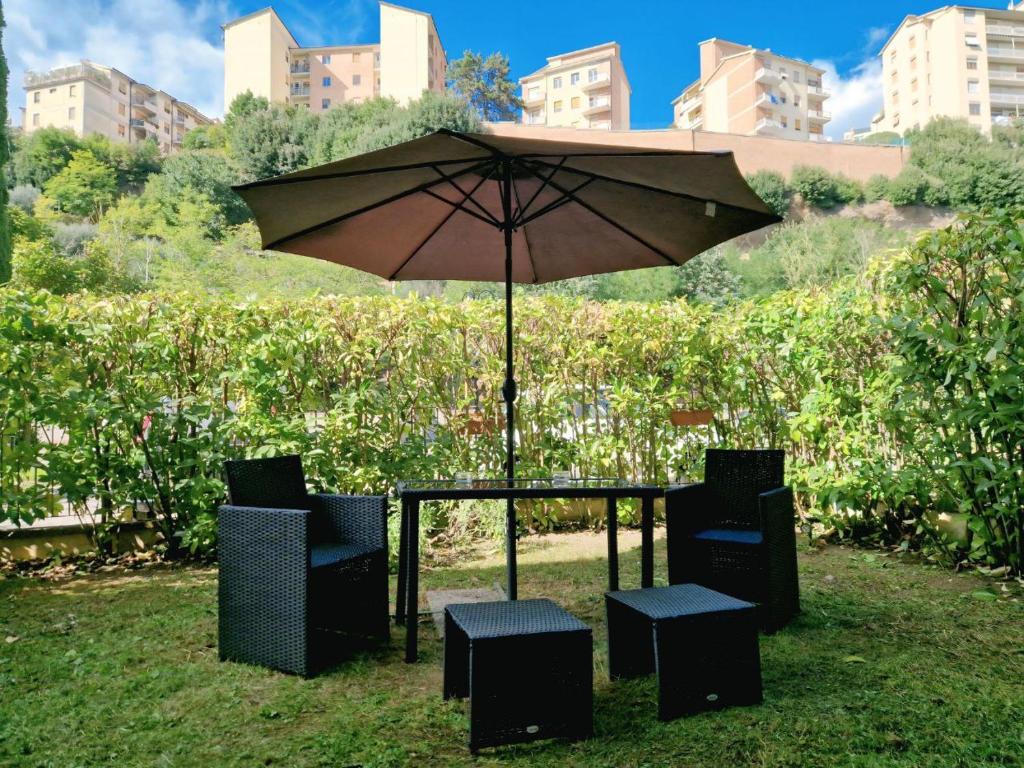 a table and chairs with an umbrella in the grass at Grazioso Appartamento a 500m da Piazza del Campo - ZTL Free in Siena