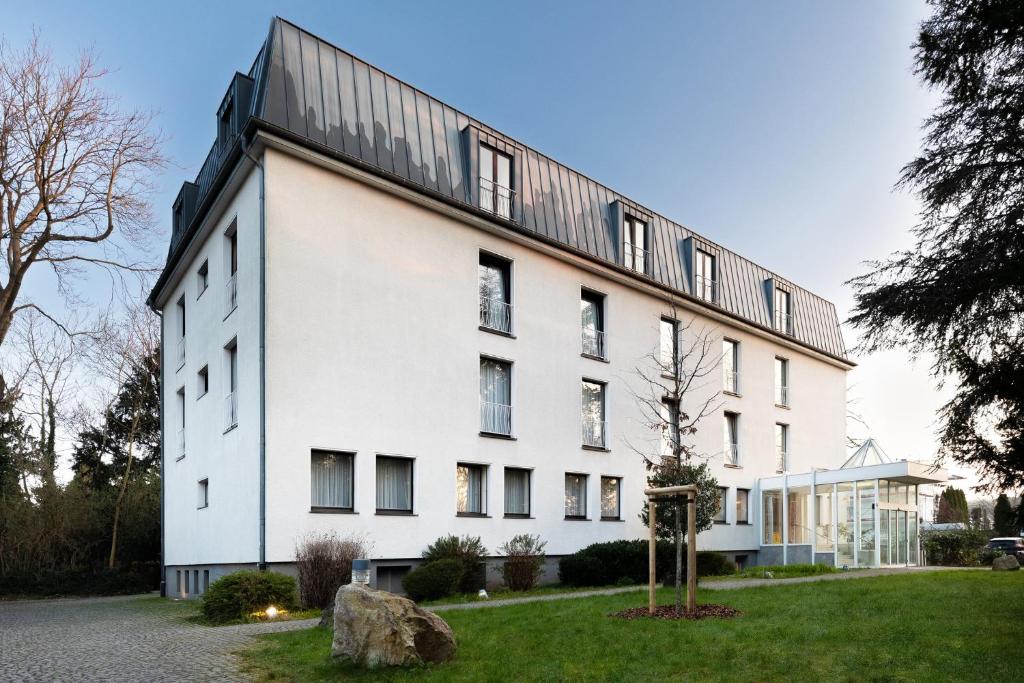 a white building with a black roof at Garner Hotel Cologne East by IHG in Cologne